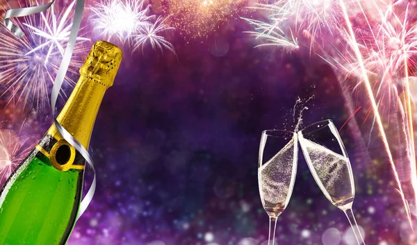 Bottle of champagne with glasses over fireworks background — Stock Photo, Image