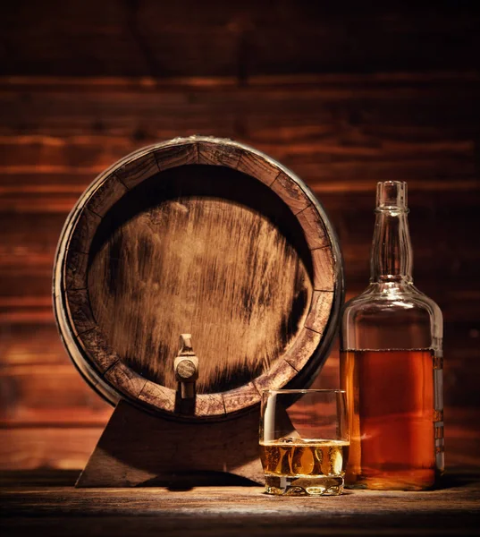 Bicchiere, bottiglia e fusto di whisky con cubetti di ghiaccio serviti su legno — Foto Stock