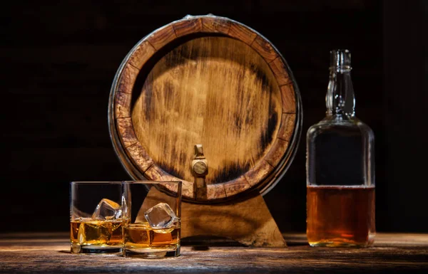Verres, bouteille et fût de whisky avec glaçons servis sur bois — Photo