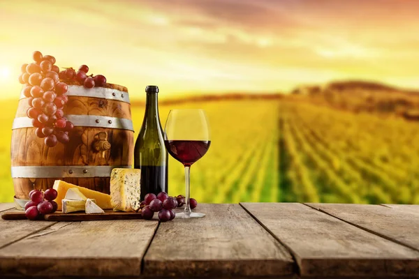 Red wine served on wooden planks, vineyard on background — Stock Photo, Image