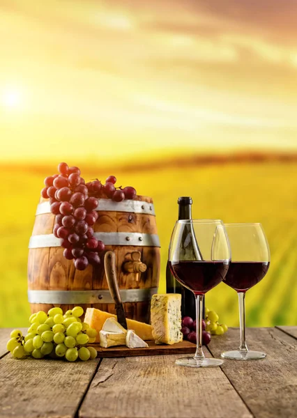 Red wine glasses served on wooden planks, vineyard on background — Stock Photo, Image