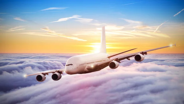 Huge airplane flying above clouds in dramatic sunset — Stock Photo, Image