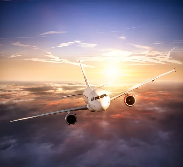 Airplane flying above clouds in dramatic sunset — Stock Photo, Image