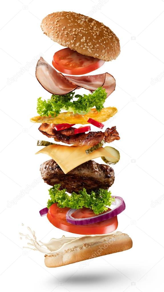 Maxi hamburger with flying ingredients on white background