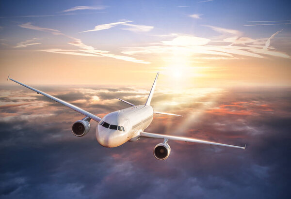 Airplane flying above clouds in dramatic sunset