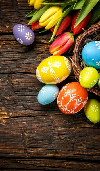 Easter eggs with tulips on wooden board — Stock Photo, Image