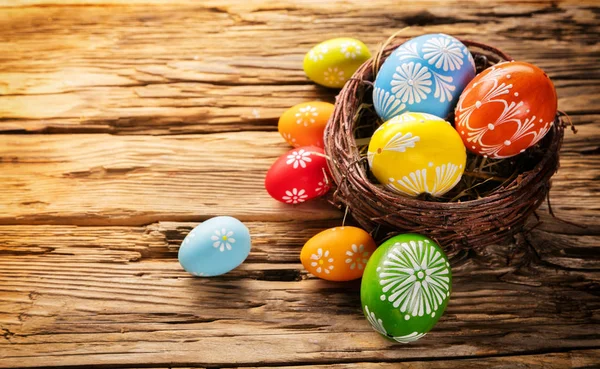 Uova di Pasqua in cesto poste su tavola di legno — Foto Stock