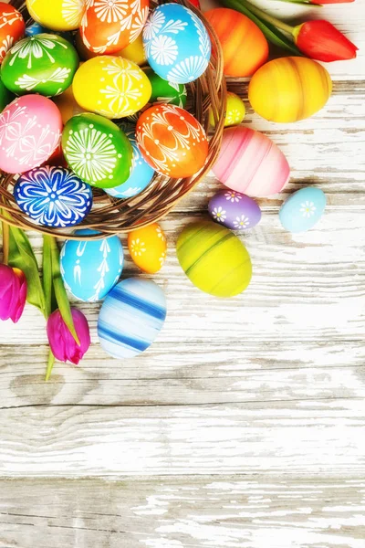 Uova di Pasqua con tulipani su tavola di legno — Foto Stock