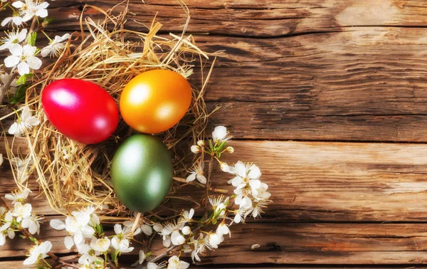 Uova di Pasqua in nido poste su tavola di legno — Foto Stock