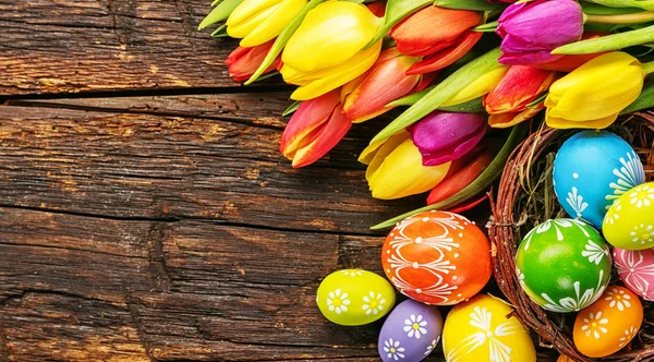 Ovos de Páscoa com tulipas em tábua de madeira — Fotografia de Stock
