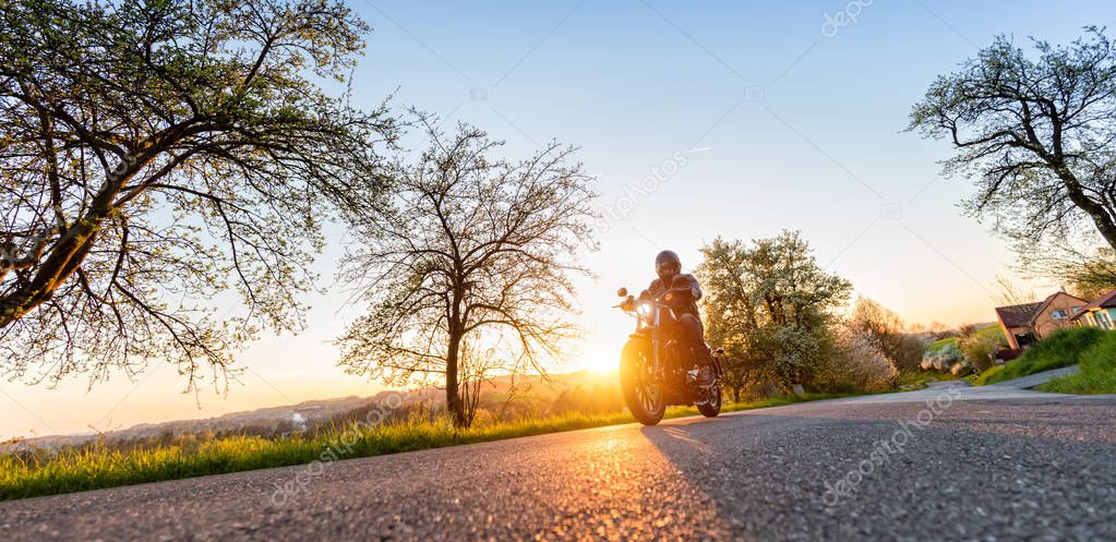 Motorcycle driver driving in beautiful sunset light
