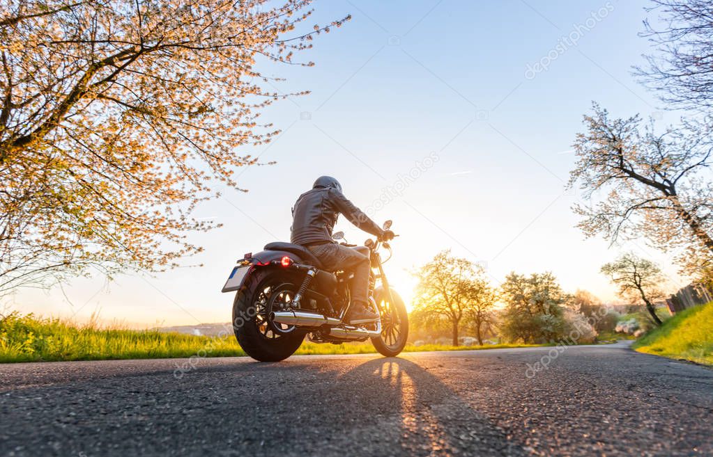 Back view of motorcycle driver driving in beautiful sunset