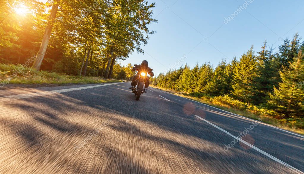 Motorcycle driver driving in beautiful sunset light