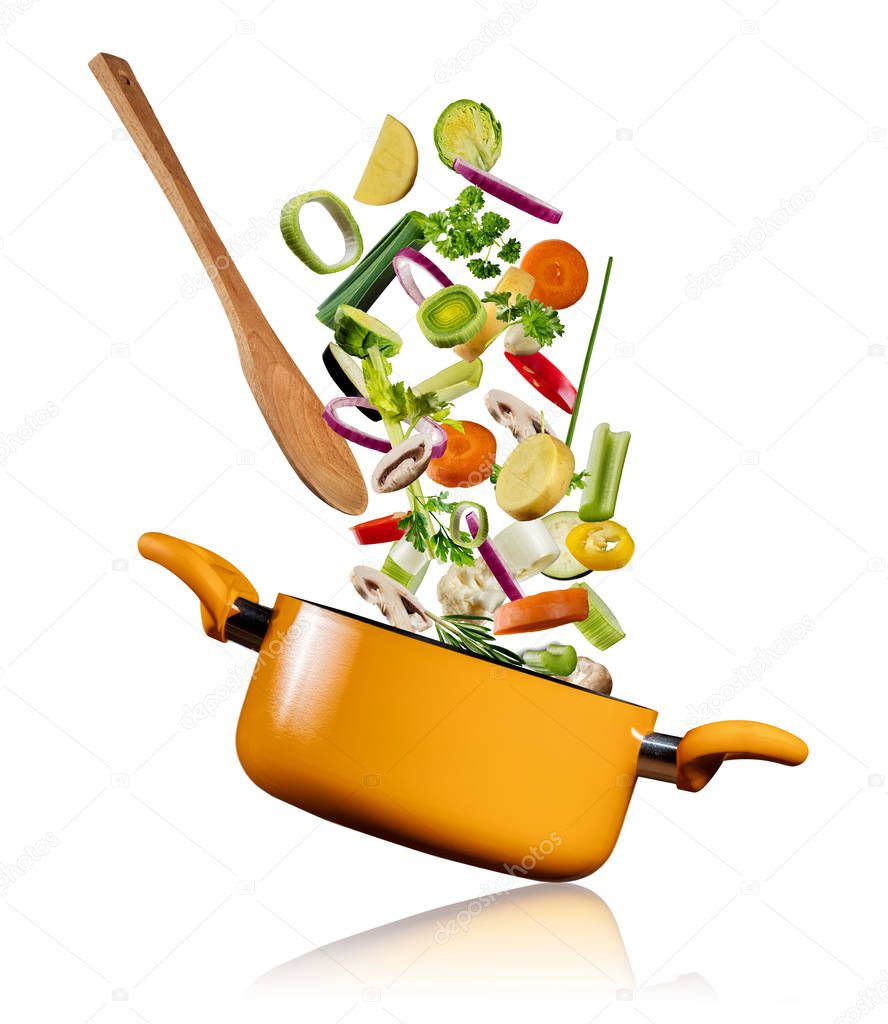 Fresh vegetables flying into a pot on white background
