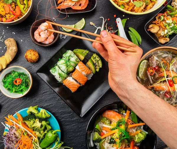 Мужская рука с палочками для еды, азиатская еда — стоковое фото