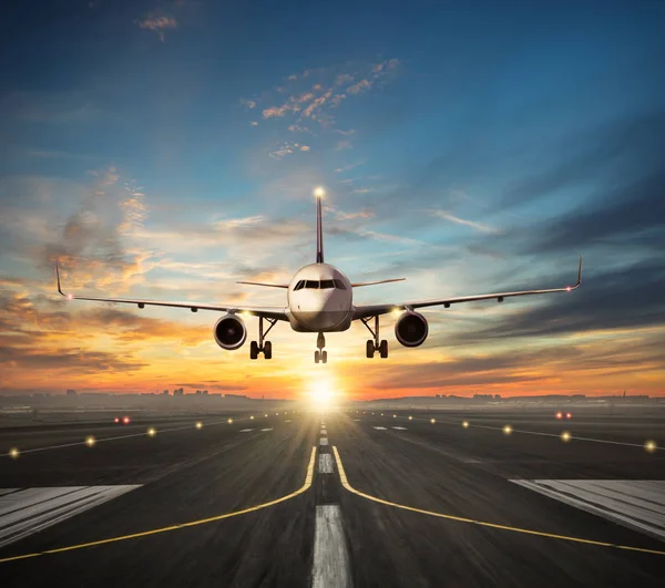 Flygplan landar till flygplatsens landningsbana i solnedgången ljus — Stockfoto