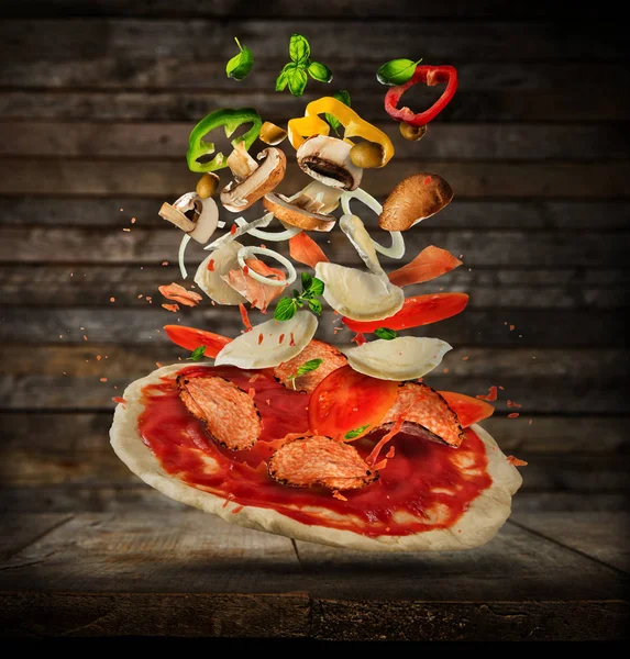 Pizza hamuru, ahşap arka plan üzerinde uçan malzemelerle