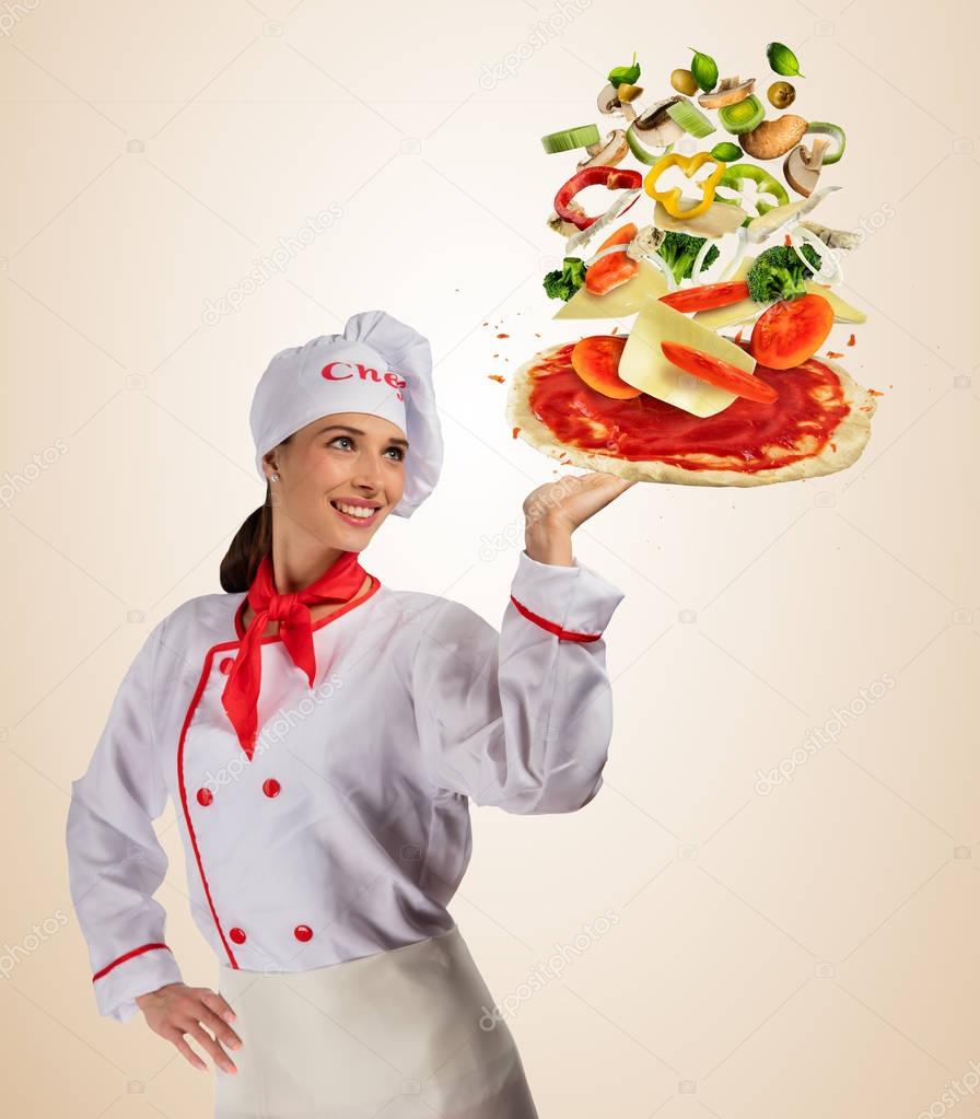 Young woman chef with Flying ingredients on pizza dough