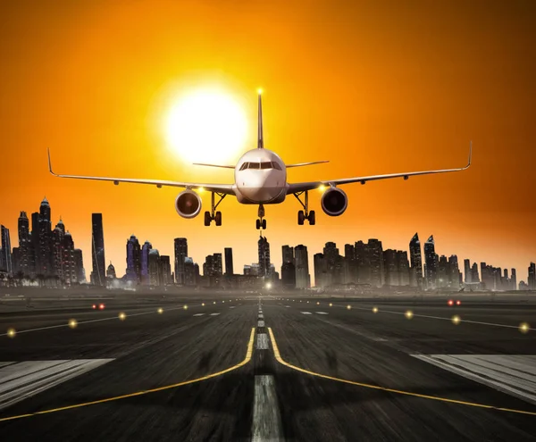 Landing commercial airplane at the runway, modern city on background — Stock Photo, Image
