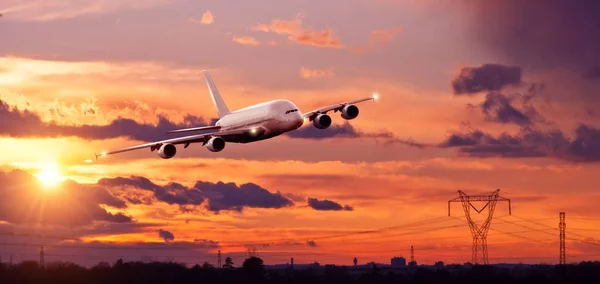 Commercial airplane flying above city in sunset ligt — Stock Photo, Image