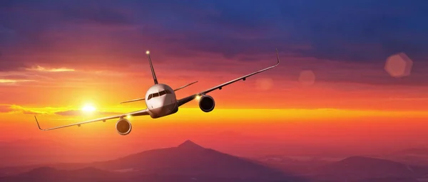 Kommersiella flygplan flyger över berg i solnedgång — Stockfoto