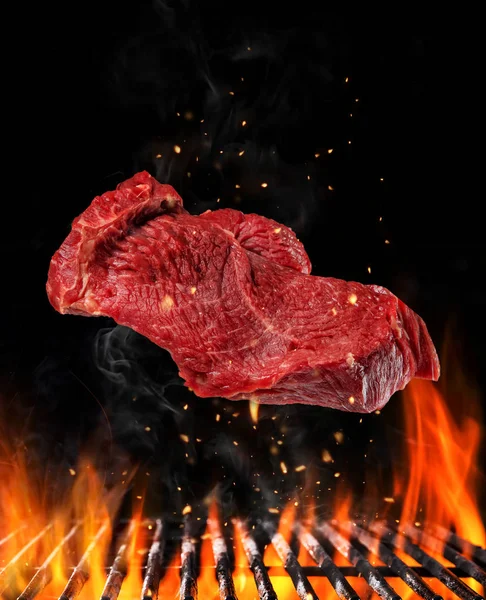 Flying raw steak over grill, food preparation concept — Stock Photo, Image