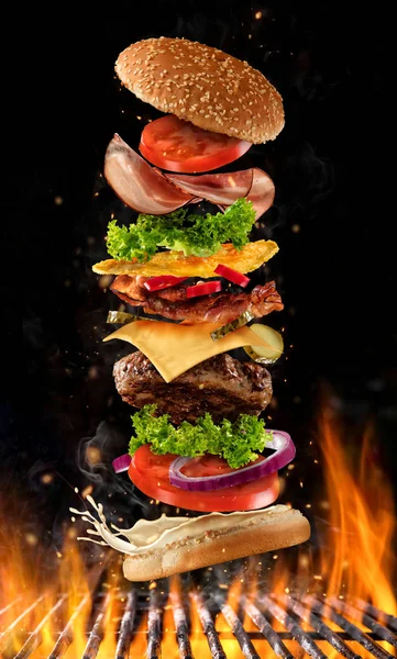 Vliegende Hamburger ingrediënten boven grill — Stockfoto