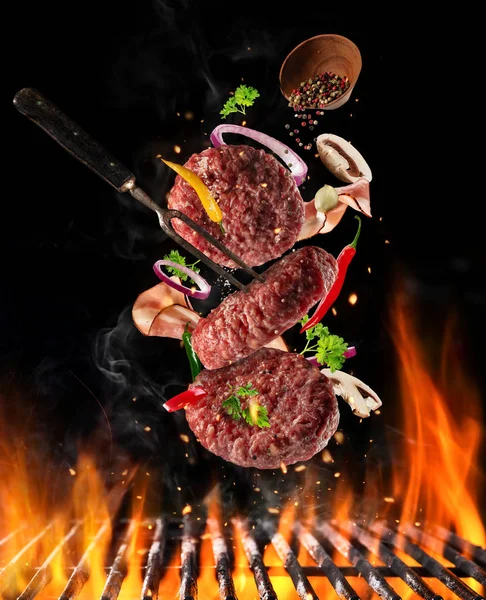 Flying raw milled beef meat with ingredients above grill fire — Stock Photo, Image