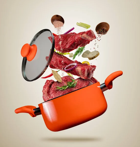Fresh beef meat and meat flying into a pot on gray background — Stock Photo, Image