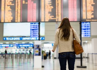 Genç kadın Havaalanı uçuş bilgileri tahtaya bakıyor