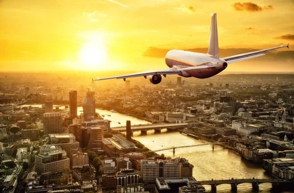 Avión de pasajeros volando sobre la ciudad de Londres bajo la luz del atardecer — Foto de Stock