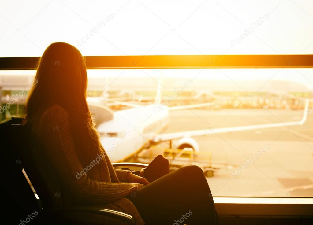 Silhouette of a young woman traveler waiting at the airport for departure