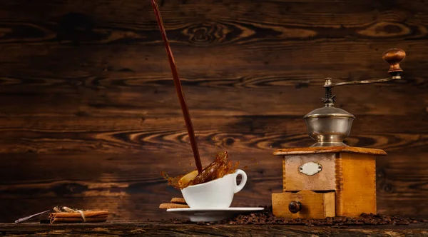 Liquido spruzzante di caffè in tazza bianca sul tavolo di legno — Foto Stock