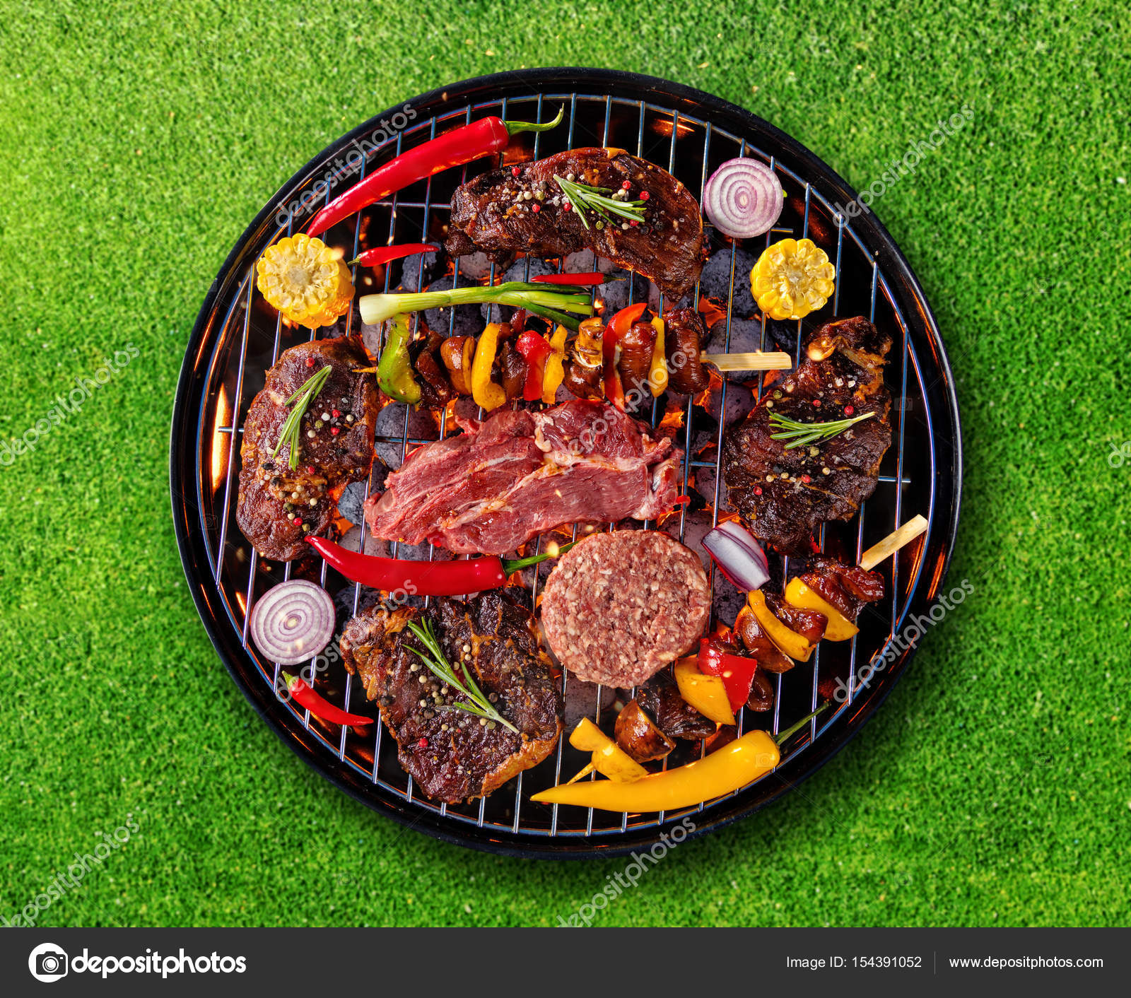 Top view of fresh meat and vegetable on grill placed on grass