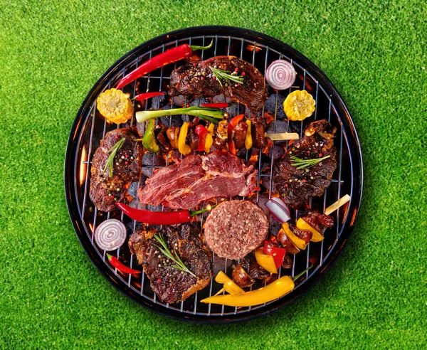Vista superior de carne fresca e vegetal na grelha colocada na grama — Fotografia de Stock