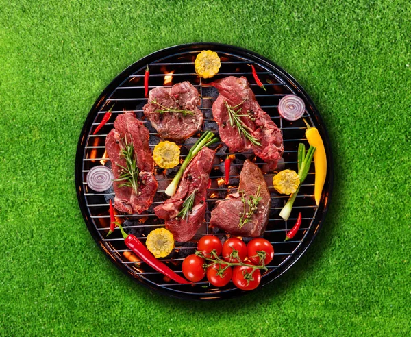 Widok z góry świeże mięso i warzywa na grillu umieszczone na trawie — Zdjęcie stockowe