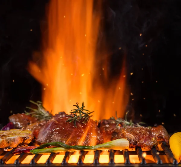 Bistecche di manzo sulla griglia, fiamme sullo sfondo — Foto Stock