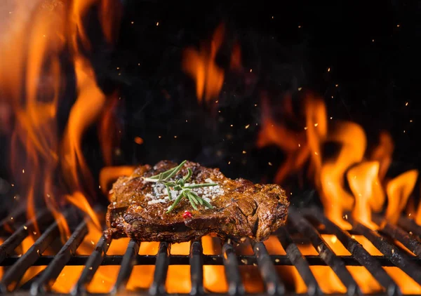 Bistecca di manzo sulla griglia, fiamme sullo sfondo — Foto Stock