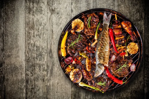 Toppsikt over ferskt kjøtt og grønnsaker på grill plassert på tregulv – stockfoto