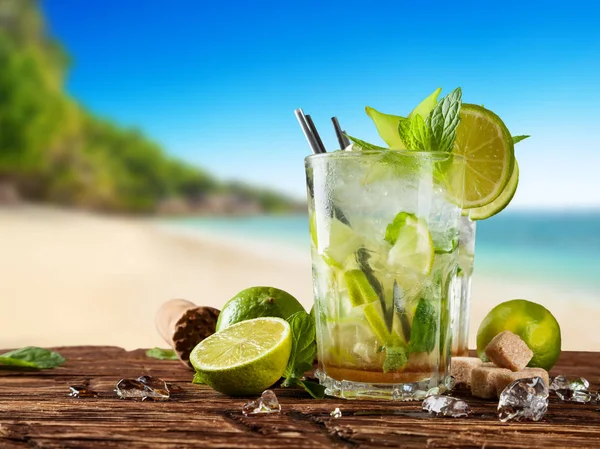 Bebidas mojito frescas colocadas en tablones de madera, playa borrosa en backg — Foto de Stock