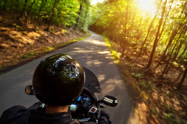 Close-up of motorbiker riding on empty road in forest — Stock Photo, Image