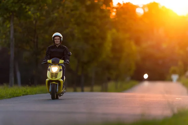 Motociclista andando em estrada vazia com céu por do sol — Fotografia de Stock