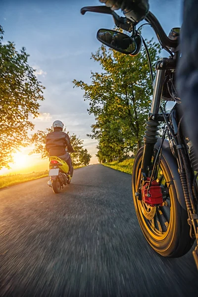 Motociclisti che guidano verso una bella luce del tramonto su vuoto — Foto Stock