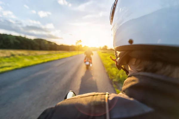 Motorbike riders driving towards beautiful sunset light on empty — Stock Photo, Image