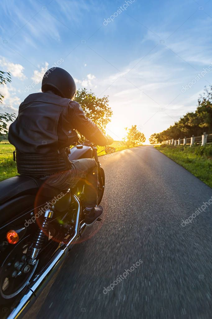 Dark motorbiker riding high power motorbike in nature with beautiful sunset light. Travel and transportation. Freedom of motorbike riding
