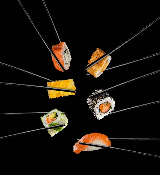 Piezas de sushi colocadas entre palillos, sobre fondo negro —  Fotos de Stock