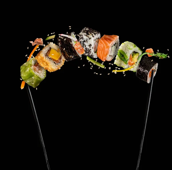 黒い背景に箸をはさんで、寿司と寿司 — ストック写真