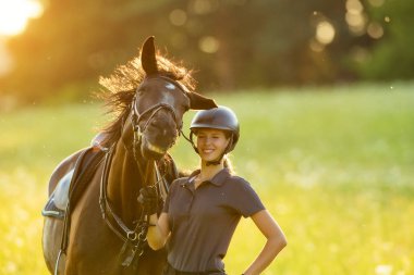 Young woman rider with her horse enjoying good mood clipart