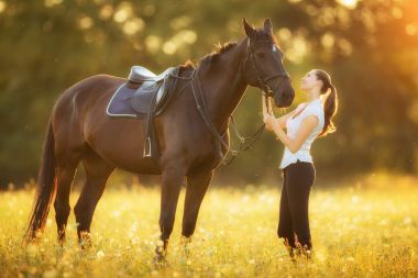 Akşam gün batımında atıyla genç bir kadın.