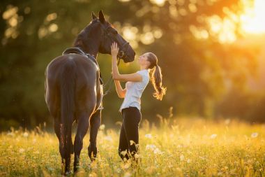 Akşam gün batımında atıyla genç bir kadın.